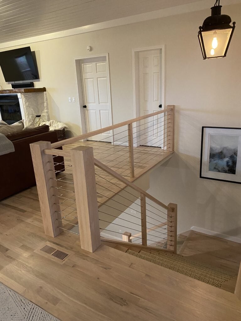 Modern wooden staircase with cable railing in a home interior.