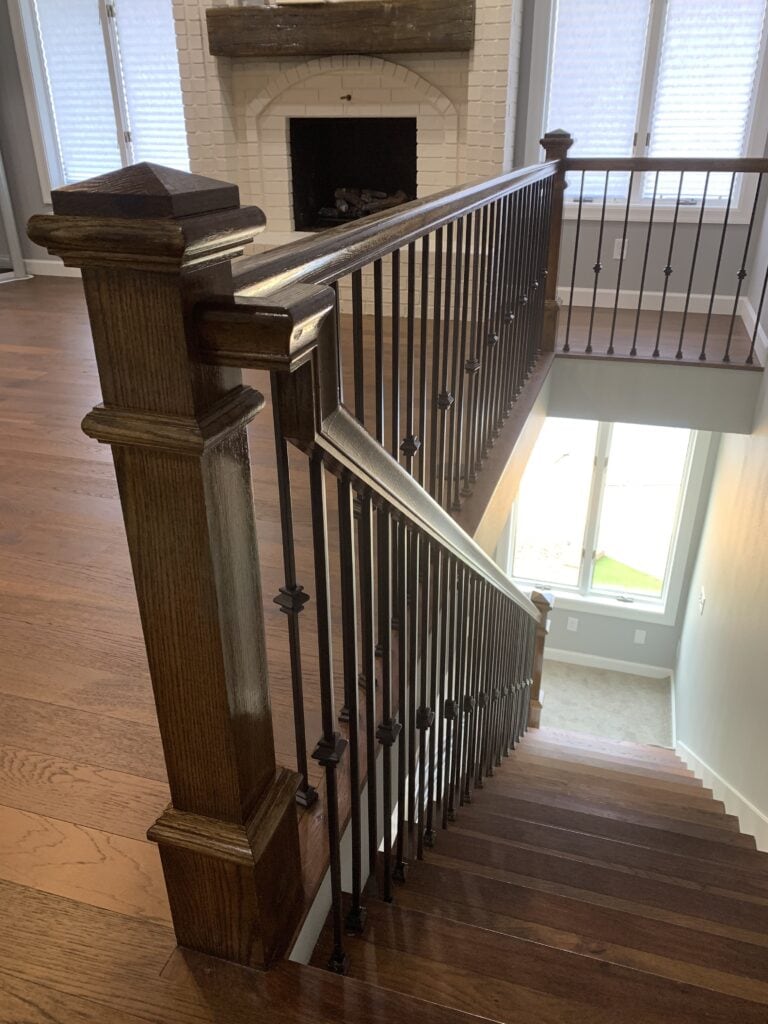 Elegant wooden staircase with black metal balusters in a modern home interior.