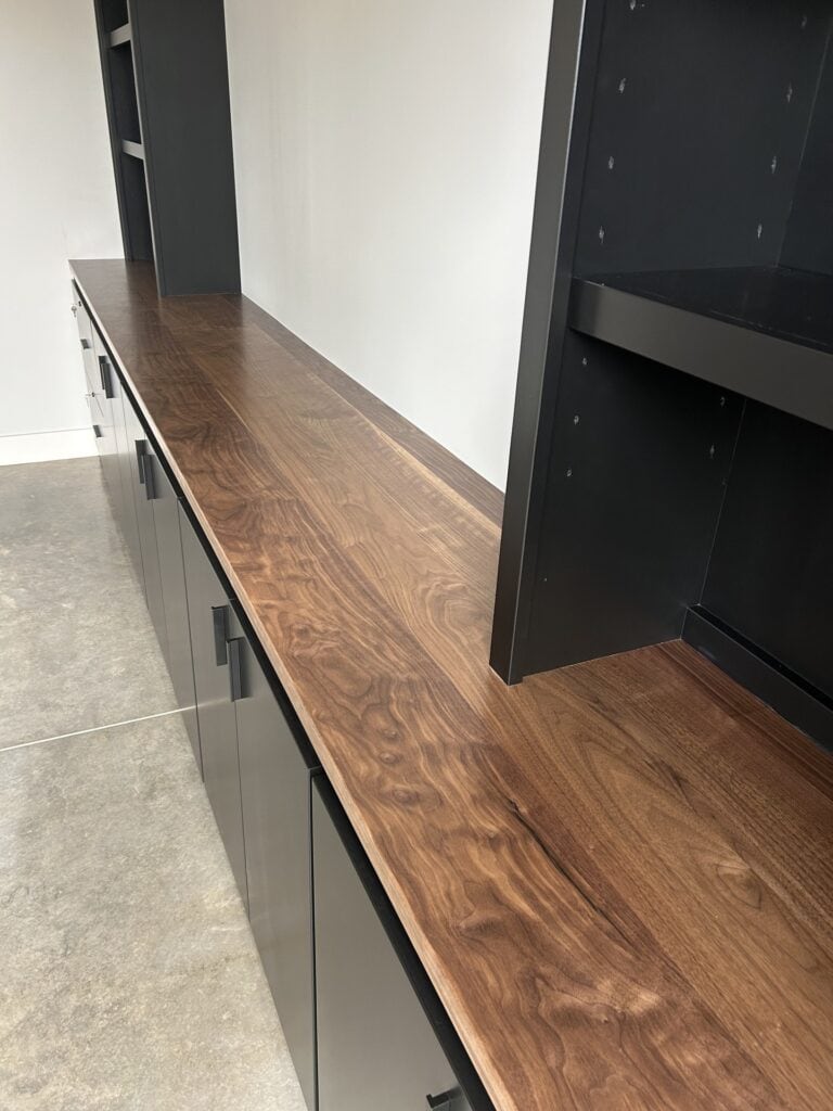 Angled view of the black cabinet unit, highlighting the depth of the cabinetry, the brass pulls, and the detailed crown molding.