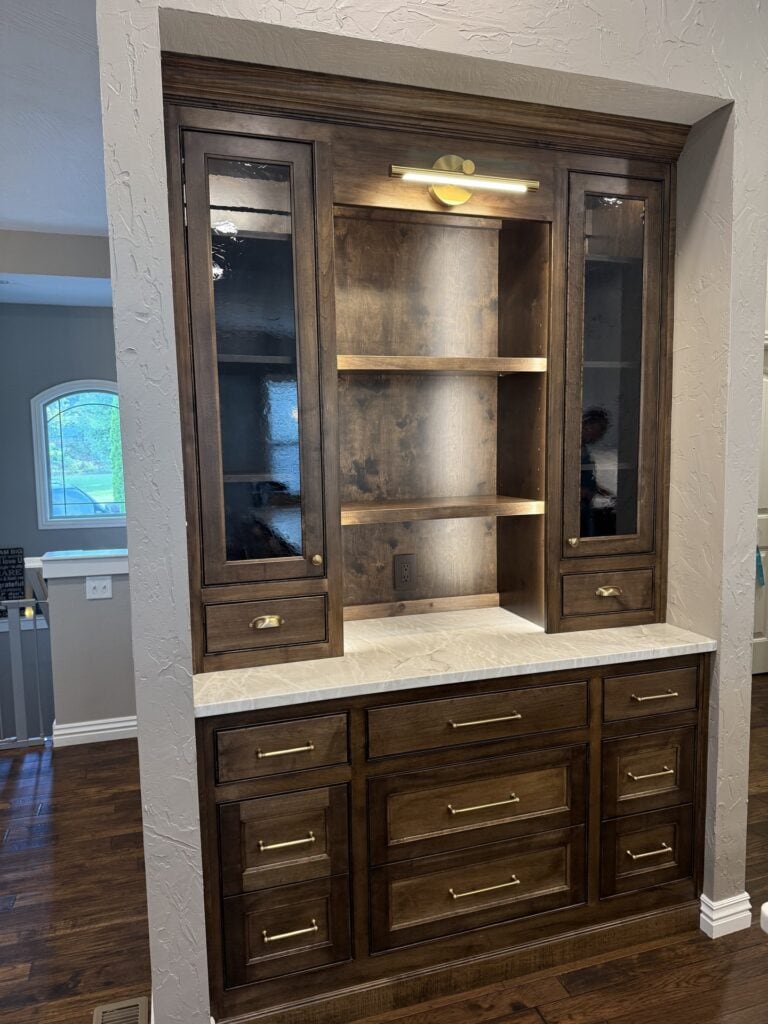 A custom built-in cabinet unit with lower storage drawers and upper display shelving, painted in a neutral tone.