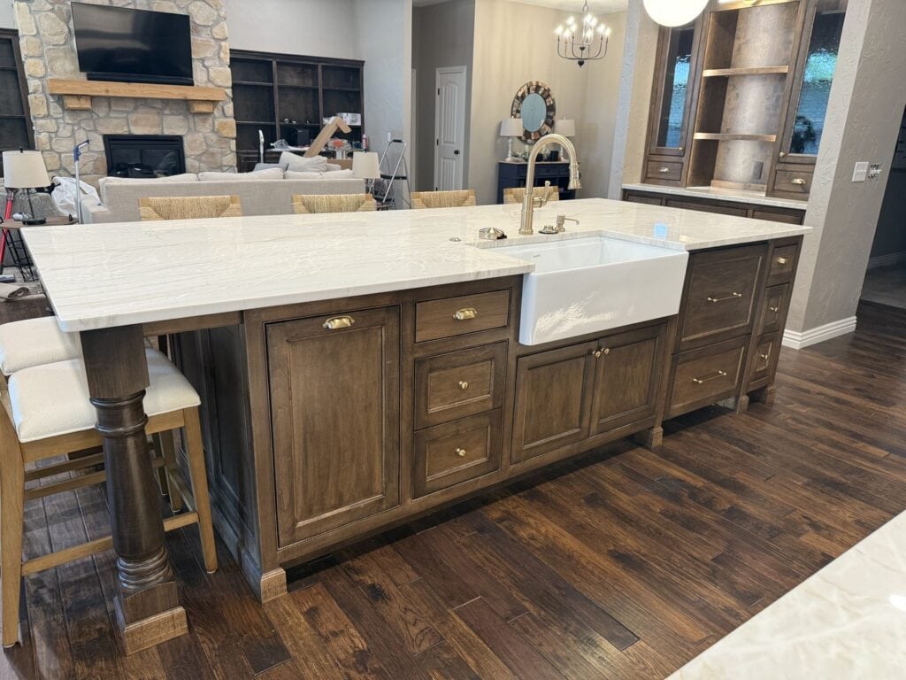 A large kitchen island featuring a white farmhouse sink, contrasting dark faucet, and ample preparation space.
