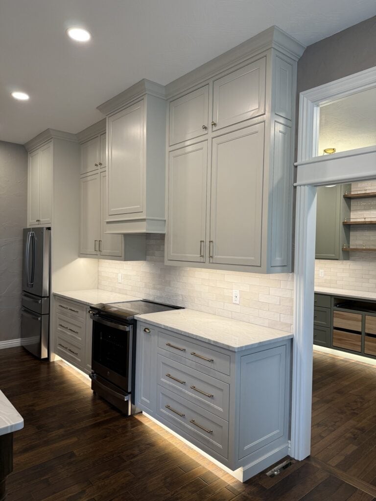 View of the kitchen wall featuring the range, custom hood, and adjacent pantry storage with floor-to-ceiling cabinetry.
