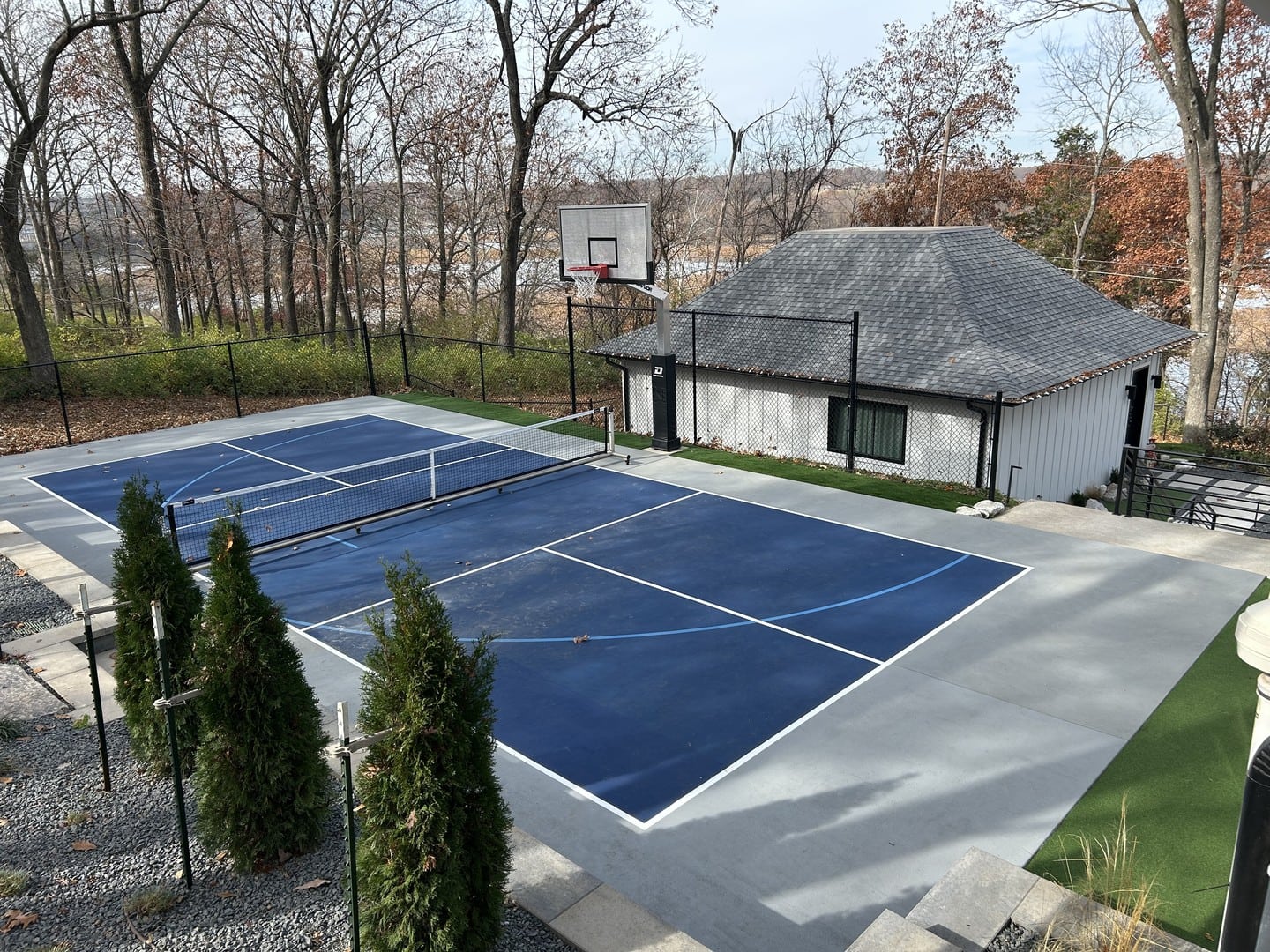View across the blue pickleball court towards a white outbuilding, showcasing the court's integration with the landscape.